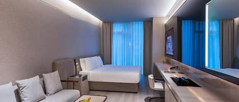 Una habitación de hotel moderna con cama, sofá, escritorio y televisión.