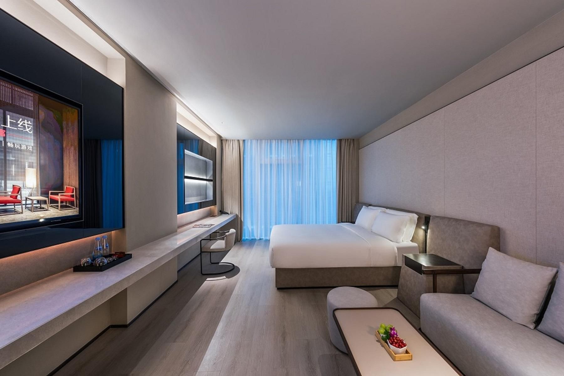 Una habitación de hotel moderna con una cama grande, un sofá, un televisor y un escritorio.