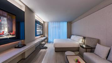 Una habitación de hotel moderna con una cama grande, un sofá, un televisor y un escritorio.