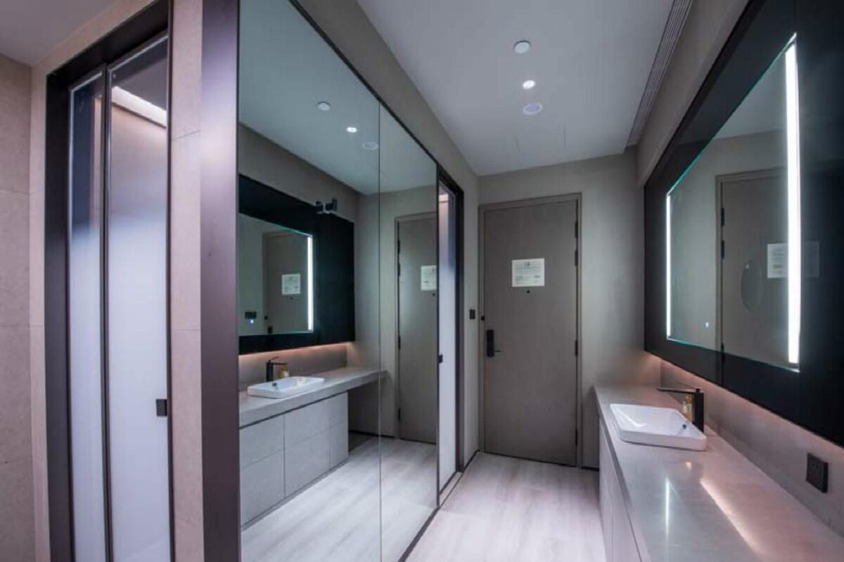 Une salle de bain moderne avec un grand miroir, un lavabo et une porte.