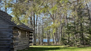 Eine Holzhütte mit Blick auf einen See und umliegende Bäume.