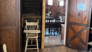 Ein rustikales Holzinterieur mit Essbereich, Holzsesseln und einem gemusterten Teppich.
