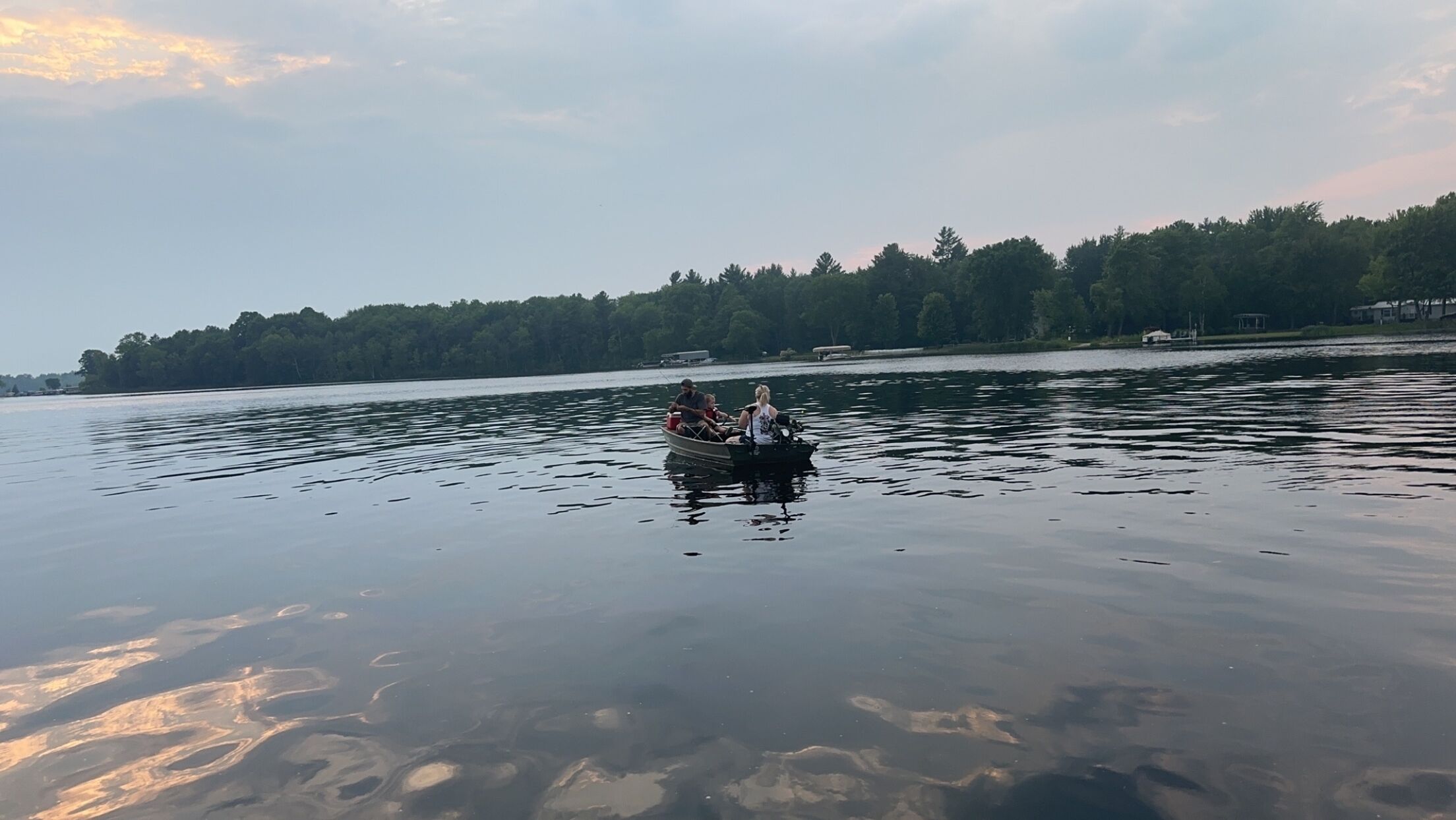A calm lake with a boat carrying two people.