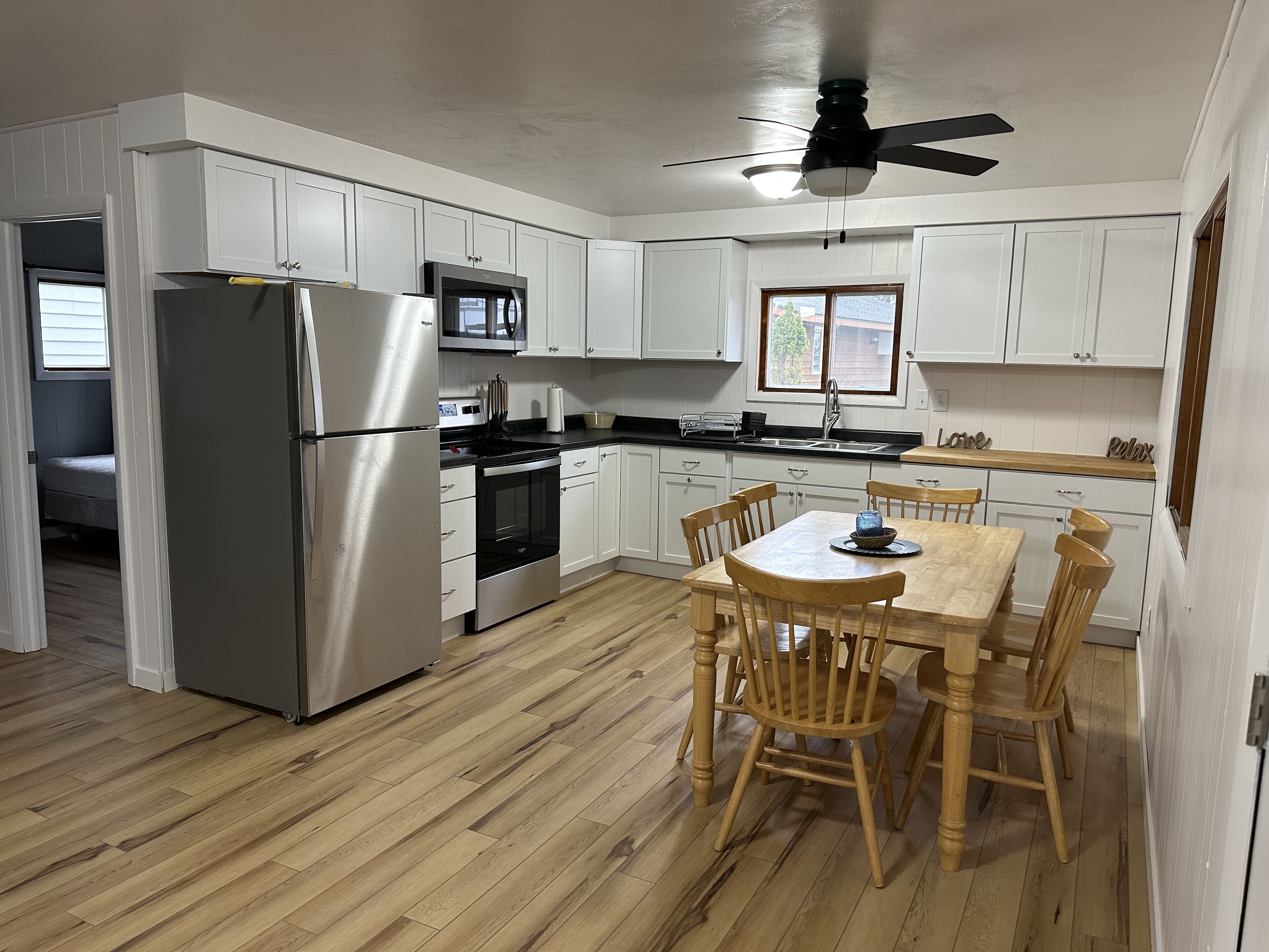 A modern kitchen with white cabinets, stainless steel appliances, and a wooden dining table.