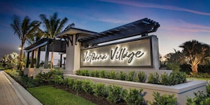 A sign for 'Verde Village' with a modern design, surrounded by well-maintained landscaping and palm trees. - New & Modern (Estero)