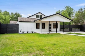 Une maison de plain-pied avec un porche à l’avant, un garage et une pelouse bien entretenue.