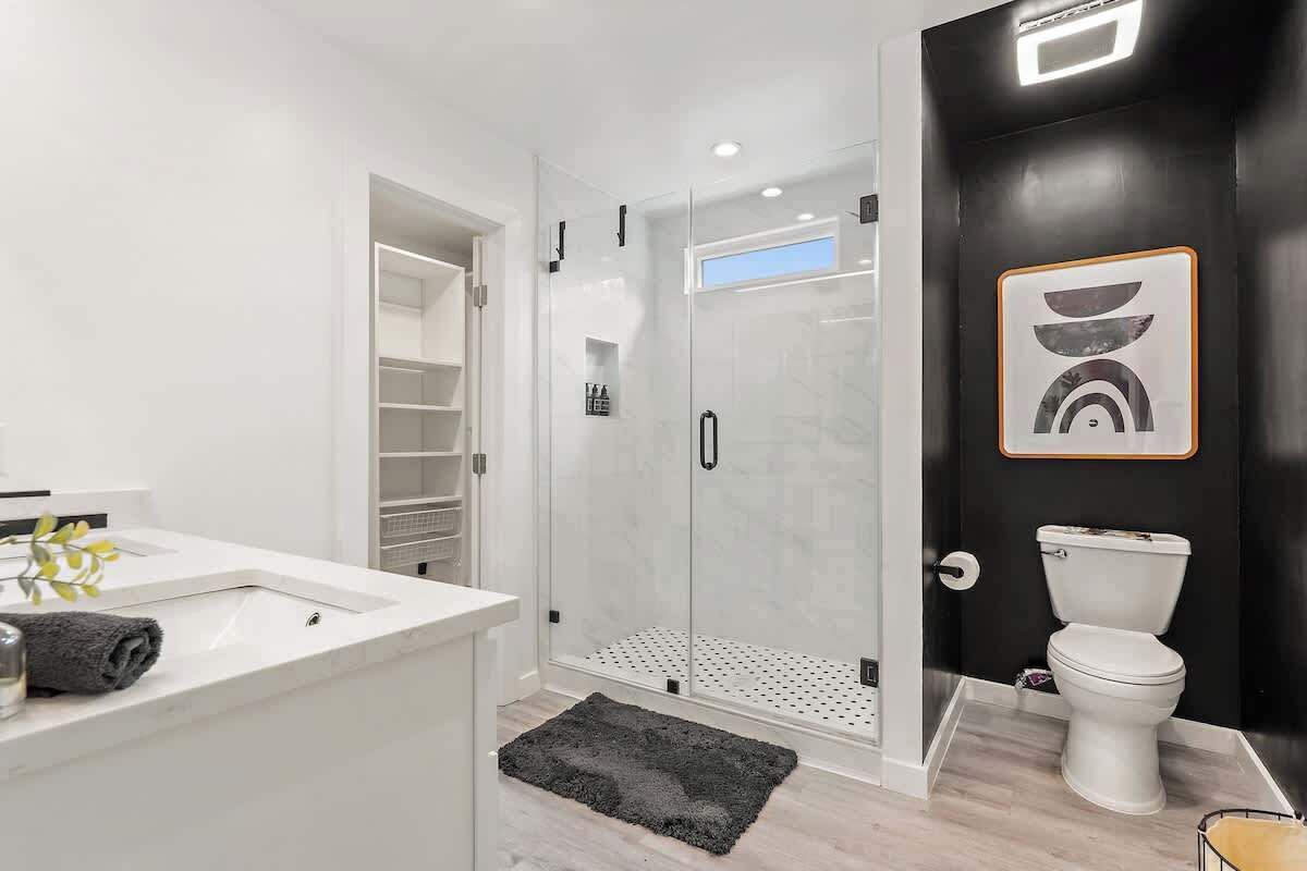 Une salle de bain moderne avec une douche à parois de verre, un lavabo blanc et des toilettes.