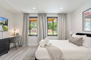 Une chambre d’hôtel moderne, dotée d’un grand lit, d’un bureau et offrant une vue sur l’extérieur.