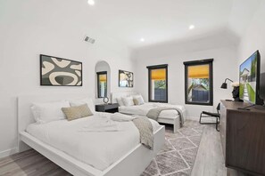 A bedroom with two beds, a desk, and artwork on the walls. - Modern 5BR | 14 Guests | Hot Tub | Mins to DT SXSW (Austin)