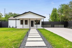A modern single-story house with a front porch, a driveway, and a well-maintained lawn. - Modern 5BR | 14 Guests | Hot Tub | Mins to DT SXSW (Austin)