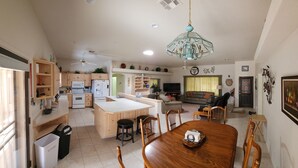 Una cucina moderna con isola centrale, mobili in legno e zona pranzo con tavolo e sedie di legno.