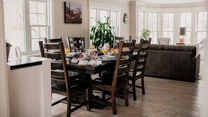 Een eetgedeelte met een houten tafel gedekt voor vier personen, omringd door stoelen, met een plant in het midden.