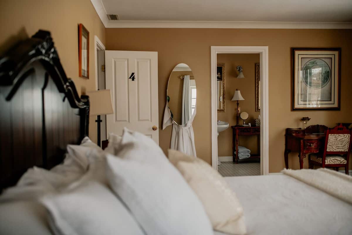 A hotel room with a bed, a desk, a chair, a mirror, and a door with the number 4.