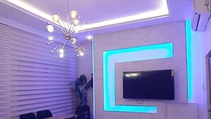 Un espace de repas moderne avec une table et des chaises, un téléviseur fixé au mur et un éclairage néon bleu original.