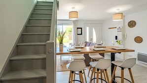 A modern kitchen with a wooden table, bar stools, and a staircase. - La Grange du Noé: Le Noé (Caen)
