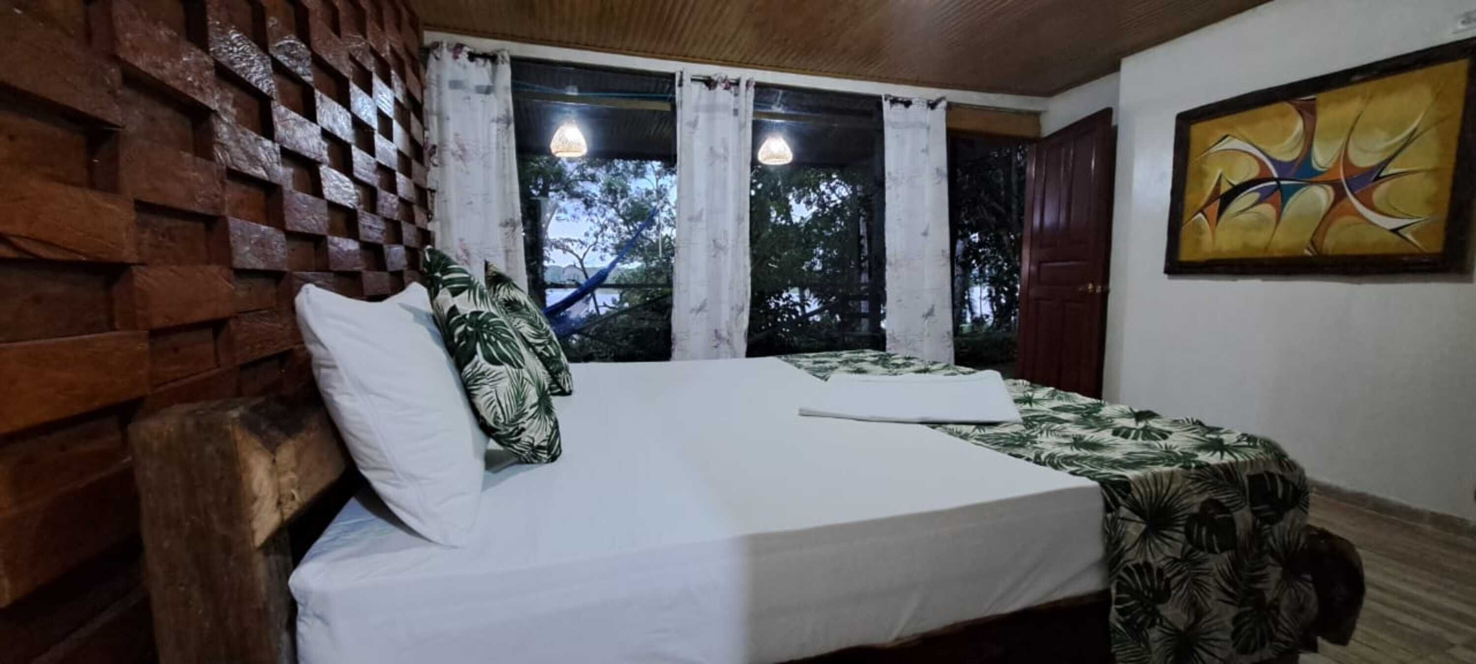 A room with a bed, a hammock, and a painting on the wall.