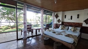 Un dormitorio con una cama grande, cabecera de madera y vistas al exterior a través de un ventanal corredero.