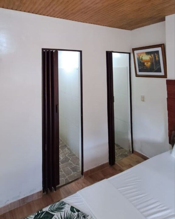 Un dormitorio con cama, techo de madera, una puerta, un espejo y un cuadro en la pared.