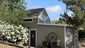 A single-story building with a gabled roof, a front door, and a large wheel feature. - Buckley Farm Casita (Menifee)