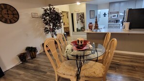 A dining area with a round glass table, four wooden chairs, and a decorative clock on the wall. - Spacious Luxury Comforters of home while enjoying time away w/community pool :) (Roseville)