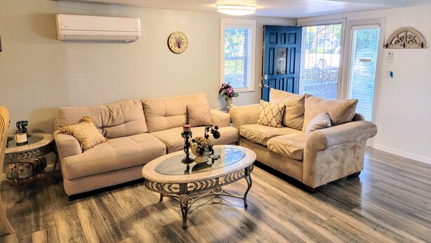 A living room with a beige sectional sofa, a glass coffee table, and a blue door. - Spacious Luxury Comforters of home while enjoying time away w/community pool :) (Roseville)