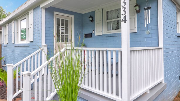 Una casa azul con detalles blancos, un porche y un buzón.