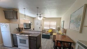 A compact kitchen with a refrigerator, stove, and dining area with a table and chairs.