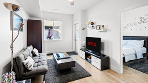 A modern living room with a sofa, coffee table, TV, and a ceiling fan.