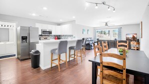 Een moderne keuken met witte kasten, roestvrijstalen apparatuur en een centraal keukenblok met barstoelen.