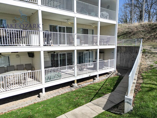 Un edificio de varios pisos con balcones, mobiliario exterior y un patio.