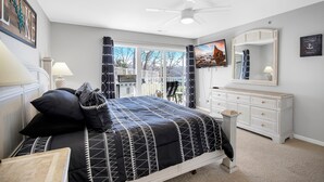 Een slaapkamer met een bed, een dressoir en een plafondventilator.