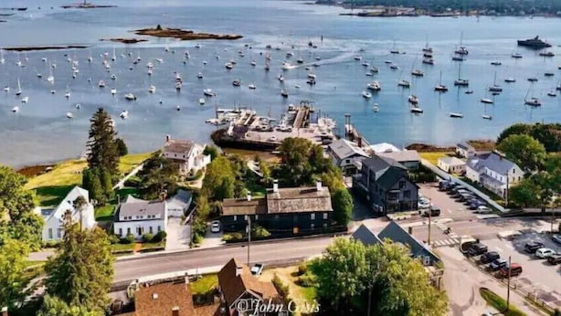 A coastal town with a marina filled with boats, surrounded by residential buildings and a clear sky. - Amazing harbor/ocean views of Pepperrell Cove (Kittery)