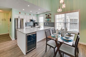 A modern kitchen with stainless steel appliances, a large island, and a dining area with a table set for four. - 8 Mi to Boardwalk: Myrtle Beach Condo Near Golfing (Myrtle Beach)