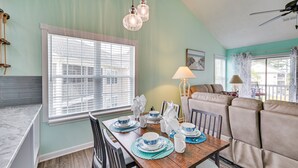 A dining area with a wooden table set for four, a sofa, and a window with blinds. - 8 Mi to Boardwalk: Myrtle Beach Condo Near Golfing (Myrtle Beach)
