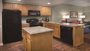 A compact kitchen with wooden cabinets, a black refrigerator, a microwave, a stove, and a dishwasher. - 1BD Deluxe/Branson - Pools, Gym, BBQ, Game Room! (Branson)