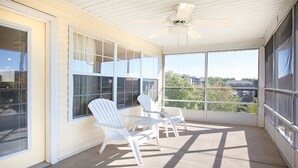 A sunlit room with large windows, white chairs, and a ceiling fan. - 1BD Deluxe/Branson - Pools, Gym, BBQ, Game Room! (Branson)