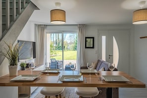 A dining area with a wooden table, four chairs, and two wine glasses.