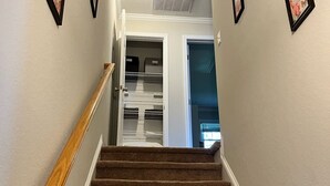 A carpeted staircase with a wooden handrail leading to a room with a closet and a door.