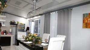 A dining area with a black table, white chairs, and a chandelier. - Rowena's River Resort with private pool  5minutes away from Our Lady of Manaoag  (Manaoag)