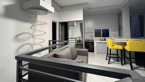 A modern living room with a staircase, a dining area with yellow chairs, and a kitchen in the background. - Rowena's River Resort with private pool  5minutes away from Our Lady of Manaoag  (Manaoag)