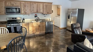 Una cocina moderna con armarios de madera, electrodomésticos de acero inoxidable y un comedor con mesa y sillas.