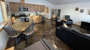 Una cocina moderna con armarios de madera, electrodomésticos de acero inoxidable y un comedor con mesa y sillas.