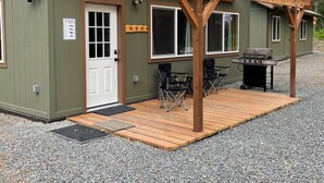 A two-story building with a covered patio area, a grill, and outdoor seating. - Soldotna Kenai Moose Lane Cottages # 3  Central to Kenai and Soldotna. (Soldotna)
