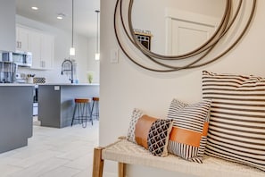 Una cocina moderna con gabinetes blancos, una isla central con taburetes e iluminación colgante.