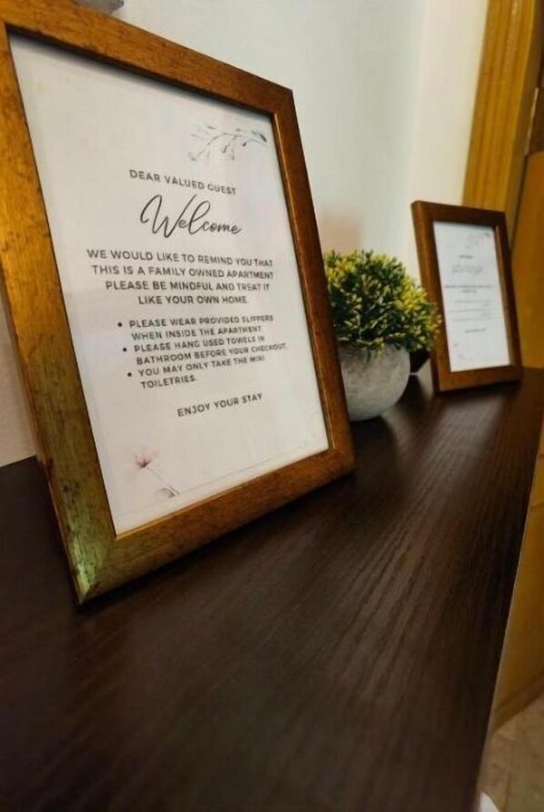 A framed welcome message for guests, advising them to be mindful of the property being a family-owned apartment and to use provided slippers and towels.