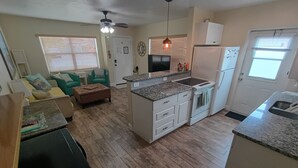 Een compacte keuken met een centraal eiland, inbouwapparatuur en een eetgedeelte met een tafel en stoelen.