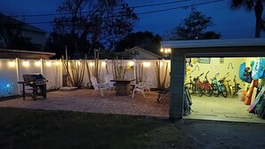 Een terras buiten met een barbecue, stoelen en een fietsenrek.