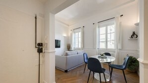 A modern living room with a sofa, chairs, a dining table, and a large window. - Luxury San Niccolò in Florence by Mmega (Firenze)