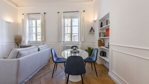 A modern living room with a sofa, a dining table with chairs, a bookshelf, and a window with curtains. - Luxury San Niccolò in Florence by Mmega (Firenze)