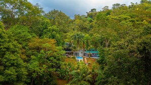 Ein abgelegenes Haus, umgeben von dichtem tropischem Regenwald, mit sichtbarem Swimmingpool und einer kleinen Liegefläche.